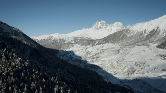 Aerial drone camera shot of mount Ushba standing in Svaneti region, Georgia, Caucasus mountains. This is daytime shot of the local valley and Ushba in the background.
