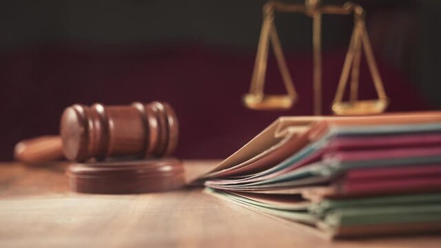 Rack focus from hammer to files, group of files placing on judge table covered with dust - concept of pending old cases or work at judicial court.