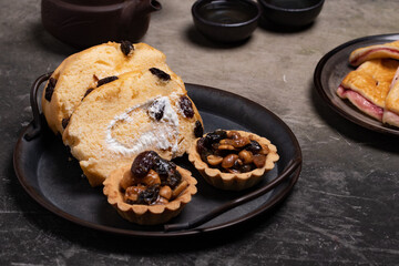 Bakery set in vintage tray, bread, jam, roll, fruit tart. Dark tone.