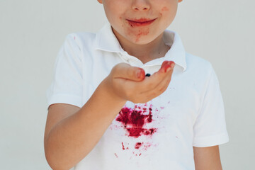 Close up children's hand holding blueberries. dirty stain on a white t-shirt. isolated on a white...