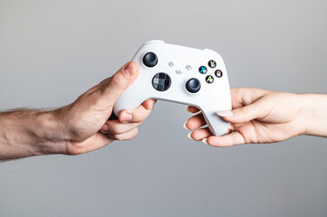 White gamepad in the hands of two people.
