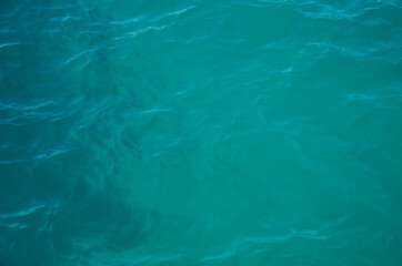 Aerial view of aquamarine sea surface. Rough sea texture. Top view natural background of rippled sea-green sea water. Marine theme with copy space.