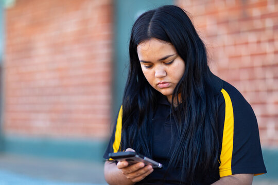 Teen girl by herself looking down at smartphone