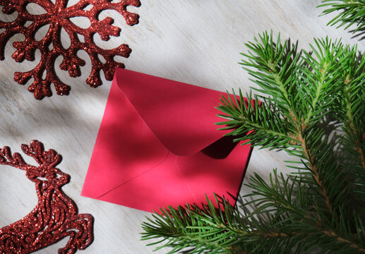 Christmas still life with branch of Christmas tree and red letter envelope . Crossed lines of shadows. Christmas composition. In dark settings