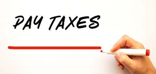Hand writing PAY TAXES with red marker. Isolated on white background.