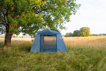 a tourist tent in nature under a tree. Summer vacation hiking