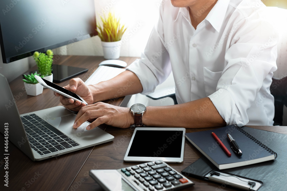 Poster man hand using mobile and typing keyboard of laptop computer on office desk. workspace, businessman 