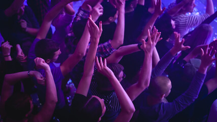 Music Festival Goers Party with Their Hands Up in the Air at a Concert in a Night Club. Shot from Above with Fans Cheering a Rock or Indie Band. Bright Colorful Strobing Lights Makes the Atmosphere