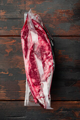 Pack with fresh beef steak cut for sous vide in vacuum plastic market bag, on old dark  wooden...