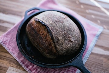 Freshly Baked, Traditionally Leavened, Homemade Sourdough Loaf of Bread in Rustic, Cast Iron Skillet 
