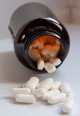 White medicinal pills are scattered from a brown bottle container close-up