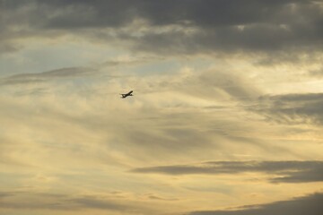 Fototapeta na wymiar Airplane in yellow sky at sunset, natural background 