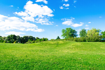 Scenic view of beautiful small mountains, hills, mounds with green grass lawn against bright blue...