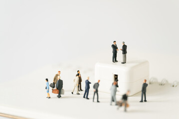 Fototapeta premium Miniature businessman shake hand partner client customers on stage with success dealing business using as contract commitment agreement investment and partnership business development joint venture