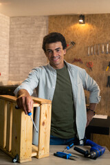 Portrait of a smiling carpenter with screwdriver in workshop