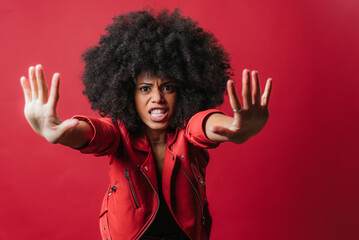 Scared black woman showing stop sign on red background