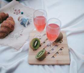 picnic by the lake, a white blanket, a woman's purse, fruit and a croissant
