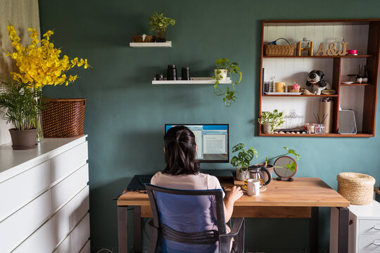 Asian woman reading document on computer and working at home