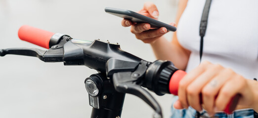 Unrecognizable woman using smartphone scaning qr code unlocking kick scooter