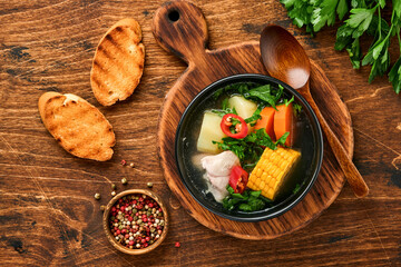 Chilean meat soup with pampkin, corn, fresh coriander and potatoes on old wooden table background. Cazuela. Latinamerican food.