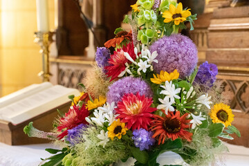 colorful bouquet of flowers on an altar with a bible and a candle in the background