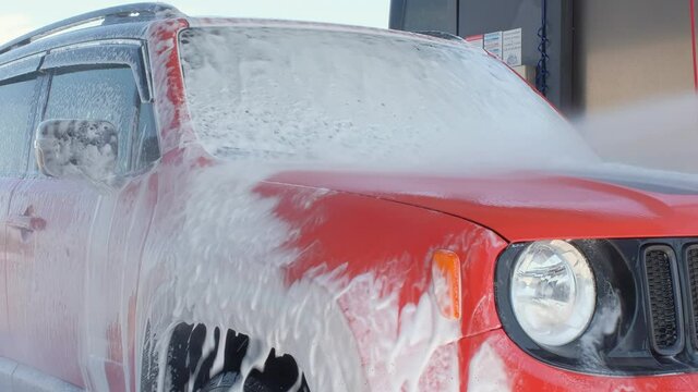 Car wash with high pressure water. The car is washed with soap at a car wash