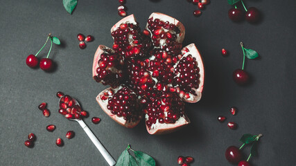 Beautiful Ripe Pomegranate Cut Open on a Dark Background, Spoonful of Pomegranate Seeds Placed Next...