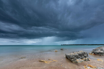 Grey storm clouds overhead with rain falling in the distance over the ocean