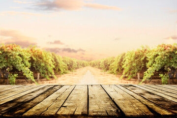 Old wooden table top with blur vineyard and grape background. Wine product tabletop country nature...