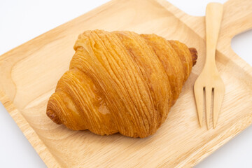 Croissant on wooden plate isolated on white background.