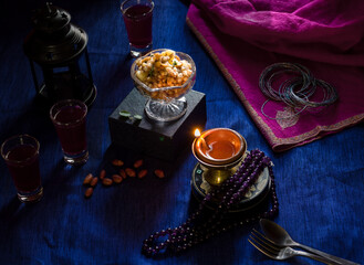 Tapioca pearl pudding also called Sabudana Khichdi is an Indian dish served on diwali. Dark and moody atmosphere created with lit up lamp,vintage lantern and pink stole on a dark background.