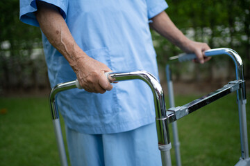 Asian senior or elderly old lady woman use walker with strong health while walking at park in happy fresh holiday.