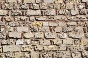 Old brickwork. Fragment of a brick wall. Bricks of different sizes in the masonry of the walls.