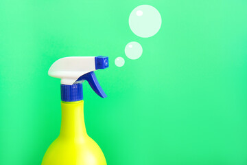 Plastic spray yellow bottle isolated on green background and painted soap bubbles. Bottle for...
