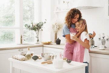 Portrait of a teen girl with her mother at home in kitchen