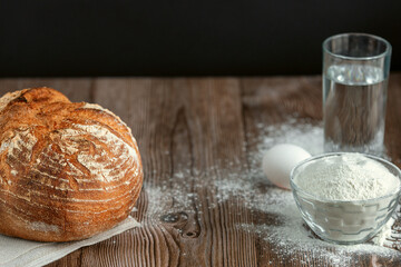 Fresh large round loaf on wooden table closeup. Fresh bread on the kitchen table. The healthy eating and traditional bakery concept. Rustic style