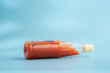 Bottled chili sauce on a blue background