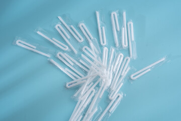White plastic straws still wrapped on a blue background