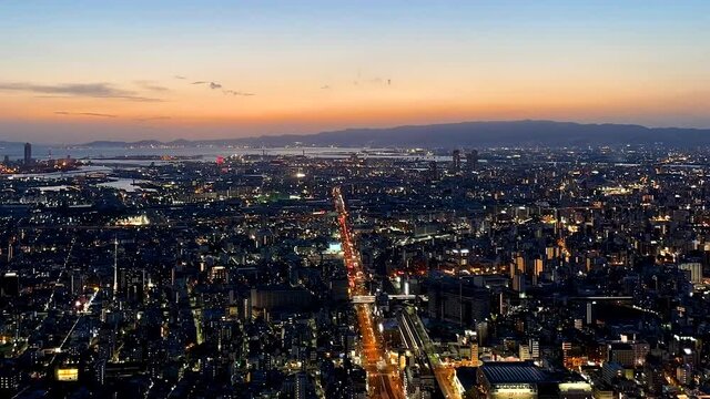 OSAKA, JAPAN : Aerial high angle sunrise view of CITYSCAPE of OSAKA. View of buildings and street traffic around Osaka bay and Kobe port. Long time lapse wide view tracking shot, night to morning.
