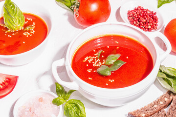 Bowls with homemade tomato soup. Ripe vegetables, fresh basil leaves, breadsticks, aromatic spices