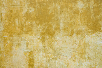 Old of dilapidated wall for texture or background, rough aged surface, remnants of peeling dirty-yellow plaster, multi-colored grunge-style crustr, strong uneven texture, above close-up wallpaper