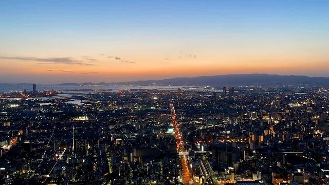 OSAKA, JAPAN : Aerial high angle sunrise view of CITYSCAPE of OSAKA. View of buildings and street traffic around Osaka bay and Kobe port. Long time lapse wide view zoom out shot, night to morning.
