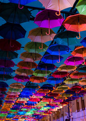 Obraz premium Colorful umbrellas in the evening. Colorful umbrellas in the sky. Street decoration from umbrellas. Background of umbrellas. 