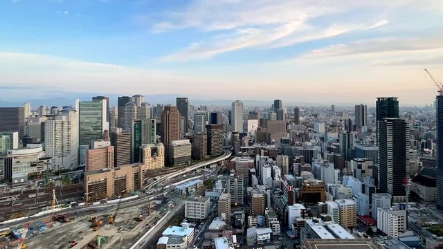 UMEDA, OSAKA, JAPAN : Aerial high angle sunrise view of CITYSCAPE of OSAKA. View of buildings and street around Osaka and Umeda station. Wide view time lapse tracking shot, night to morning.