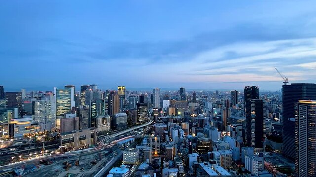 UMEDA, OSAKA, JAPAN : Aerial high angle sunrise view of CITYSCAPE of OSAKA. View of buildings and street around Osaka and Umeda station. Wide view time lapse zoom in shot, night to morning.