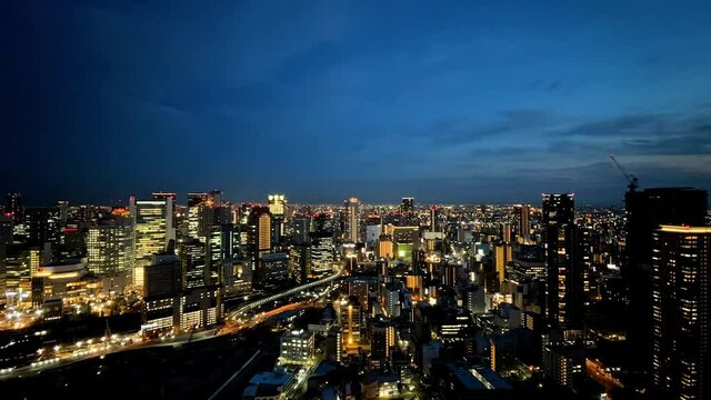 UMEDA, OSAKA, JAPAN : Aerial high angle sunrise view of CITYSCAPE of OSAKA. View of buildings and street around Osaka and Umeda station. Wide view time lapse zoom in shot, night to morning.
