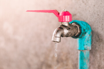 Shot of selective focus old faucet doesn't close properly and dripping water leaks out. Concept...