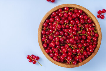 Fresh red currant in wooden bowl on dark table