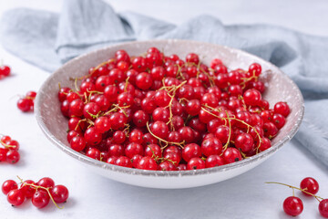 Fresh red currant in wooden bowl on grey table