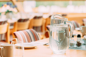 Cozy Interior Of Summer Cafe. Jug Of Icy Cold Ice Water On Table And Cutlery Laid Out
